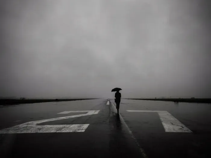 Framed Print : Lone woman with umbrella on empty runway 27 left at Tempelhof Airport in Berlin on a rainy day Framed Print : Lone woman with umbrella on empty runway 27 left at Tempelhof Airport in Berlin on a rainy day