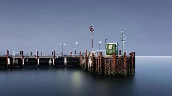 Long exposure of the illuminated harbour watchman's house at dusk during the blue hour at the harbour entrance of List on Sylt, Germany, Europe