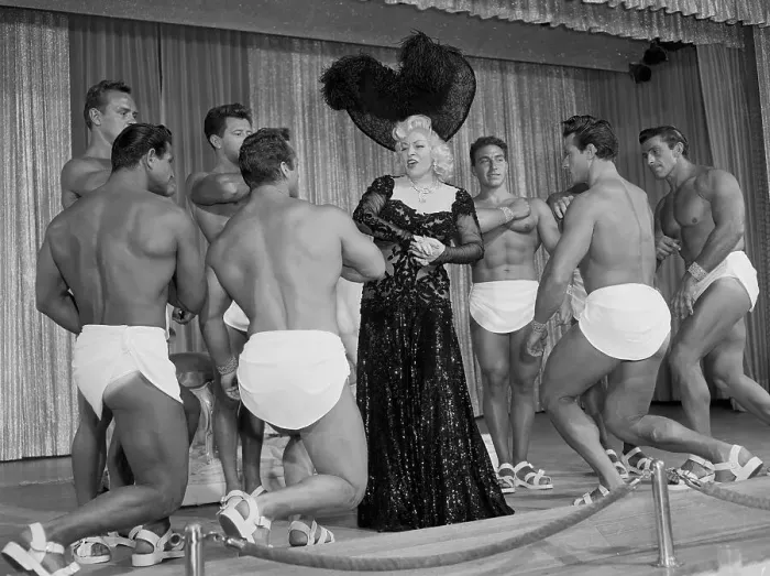 Framed Print : Mae West Posing in Center of Muscle Men