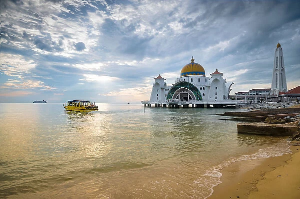 Malacca Straits Mosque Masjid Selat Melaka near Malacca Town, Malaysia with water cruiser full of tourist enjoying scenery