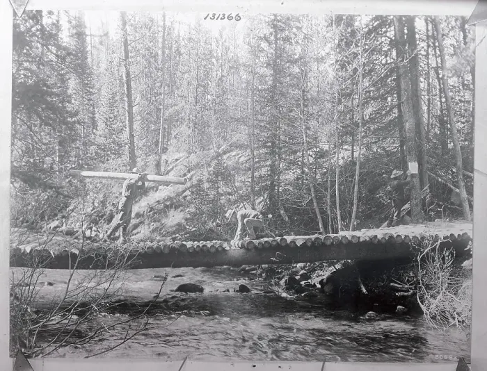 Framed Print : Man Carrying Log with Others Working on Bridge Framed Print : Man Carrying Log with Others Working on Bridge