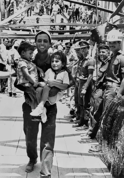 Framed Print : Man Carrying Refugee Children Framed Print : Man Carrying Refugee Children