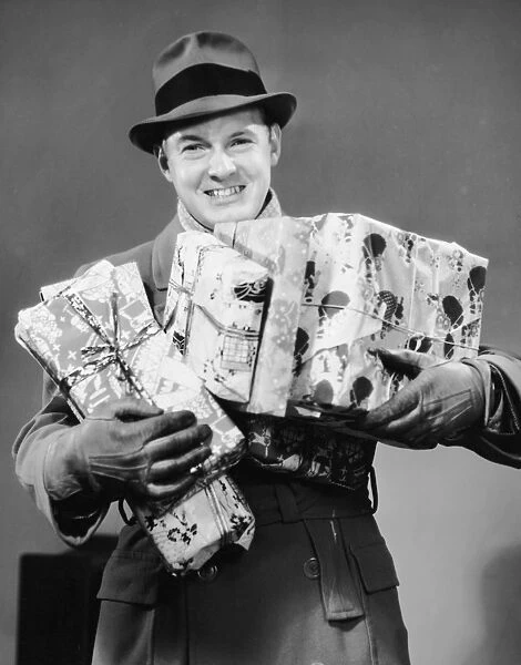 Man with coat, gloves and hat carrying Christmas gifts