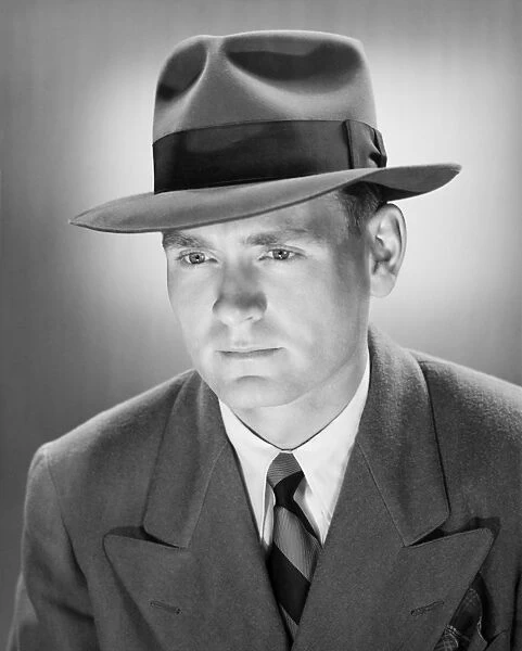 Man in Fedora hat in studio, (B&W), close-up, portrait