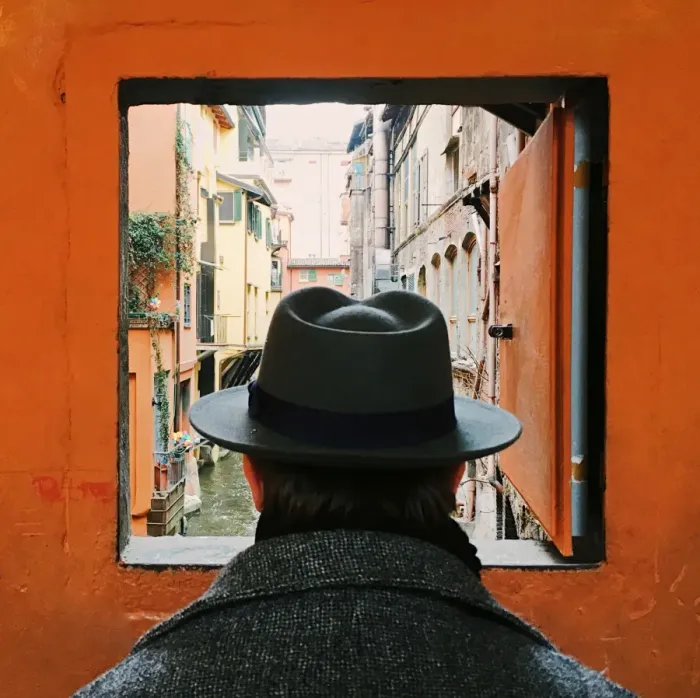 Framed Print : Man in hat looking at the canal through the window in Bologna, Italy Framed Print : Man in hat looking at the canal through the window in Bologna, Italy
