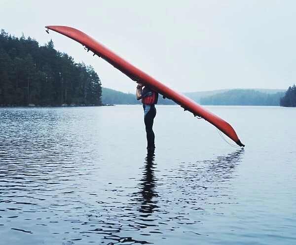 Man with kayak on head on lake surface, side view