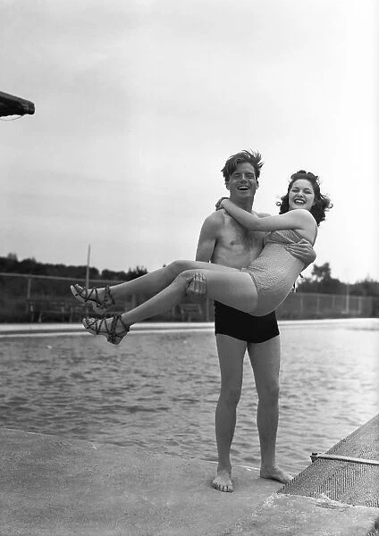 Man lifting woman at pool edge, (B&W), portrait