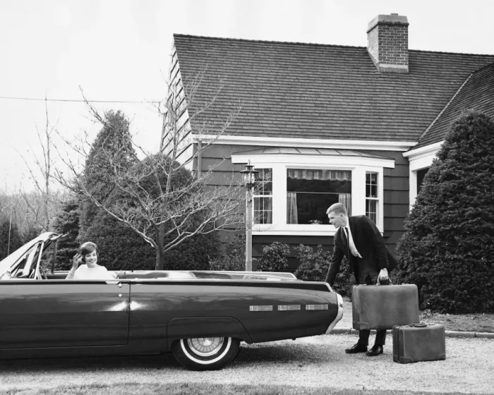 Framed Print : Man loading trunk with suitcases while woman waits in car