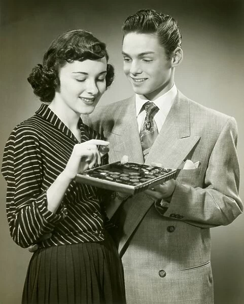 Man offering woman box of chocolates