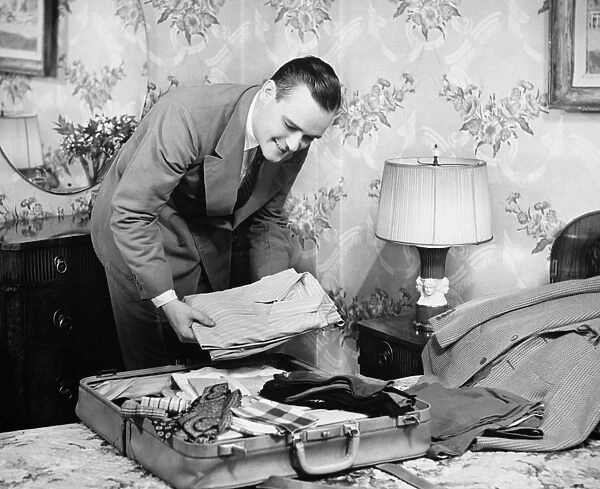 Man packing suitcase in bedroom (B&W)