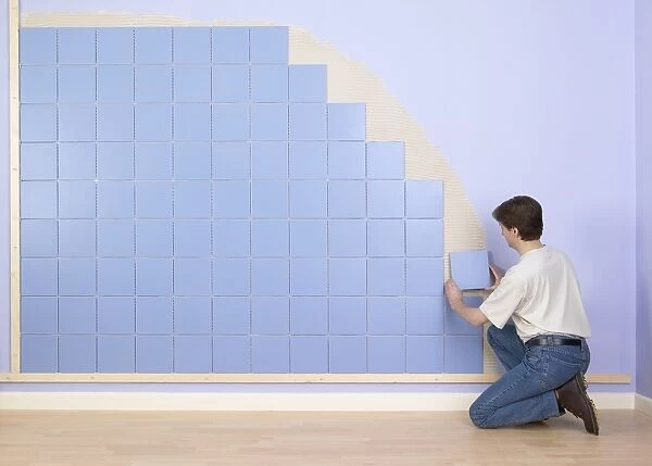 Man placing tile on wall