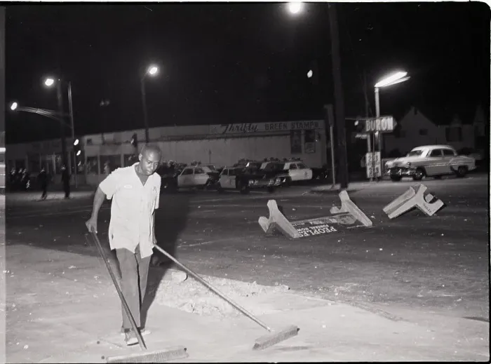 Framed Print : Man Pushing Brooms After Riot Framed Print : Man Pushing Brooms After Riot