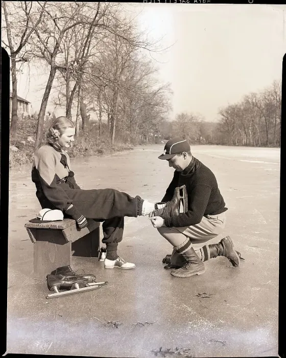 Framed Print : Man Putting on Woman's Ice Skates Framed Print : Man Putting on Woman's Ice Skates