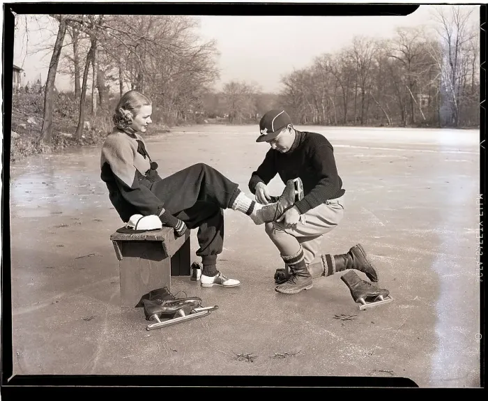 Framed Print : Man Putting on Woman's Ice Skates Framed Print : Man Putting on Woman's Ice Skates