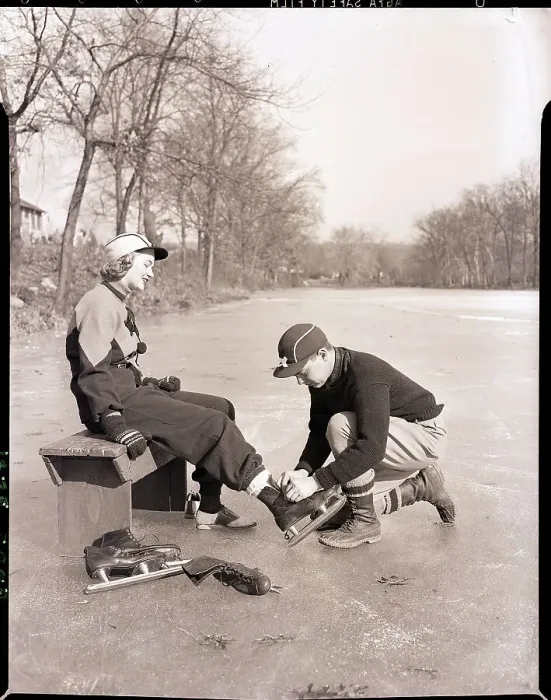 Framed Print : Man Putting on Woman's Ice Skates Framed Print : Man Putting on Woman's Ice Skates