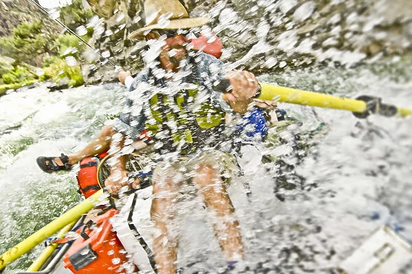 Man rowing raft through splashing rapids