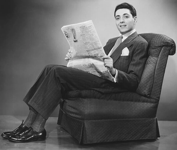 Man sitting on chair, holding newspaper (B&W)