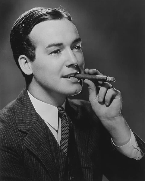 Man smoking cigar in studio, (B&W), portrait