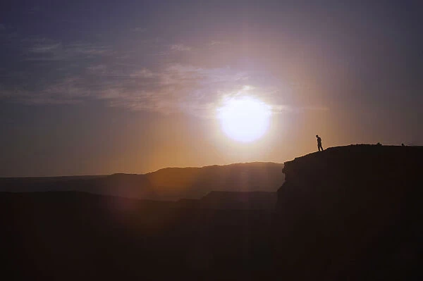 Man standing on the edge of a cliff at sunset, Valle de la Luna, San Pedro de Atacama, Chile