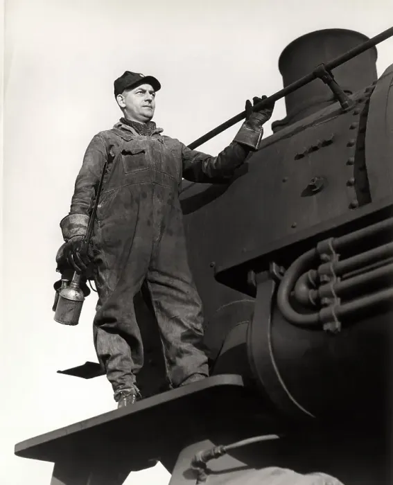 Framed Print : Man standing on train engine, holding oil can Framed Print : Man standing on train engine, holding oil can