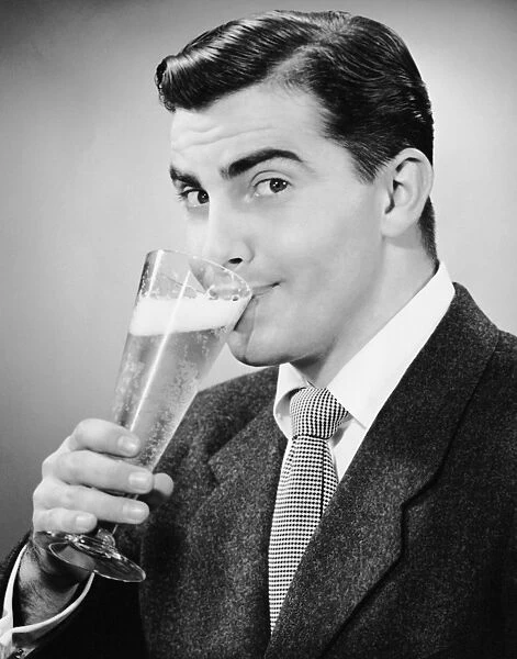 Man in suit drinking tall glass of beer