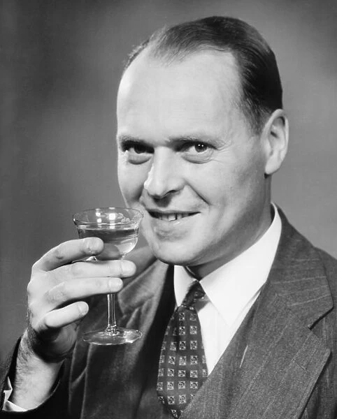 Man in full suit raising glass of wine, (B&W), close-up, portrait