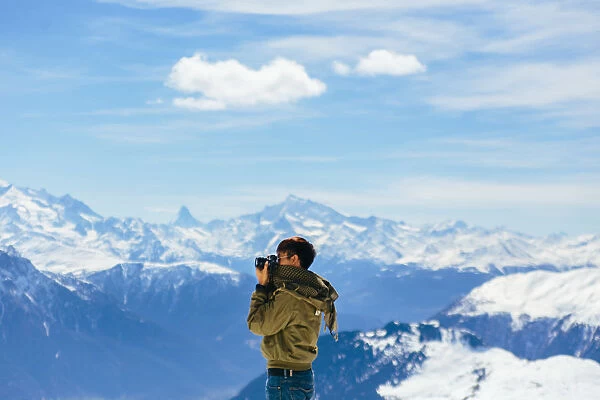 A Man taking a photo with the background of Alps