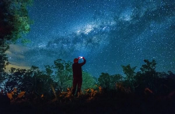 Man taking photo of night sky with smart phone