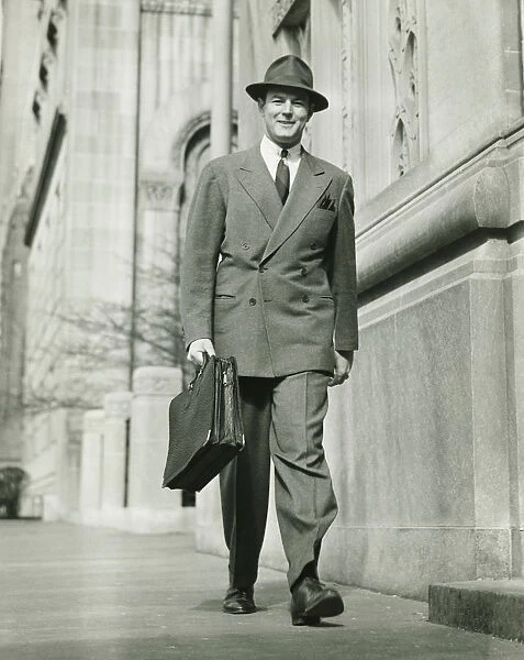 Man walking on street, carrying briefcase, (B&W)