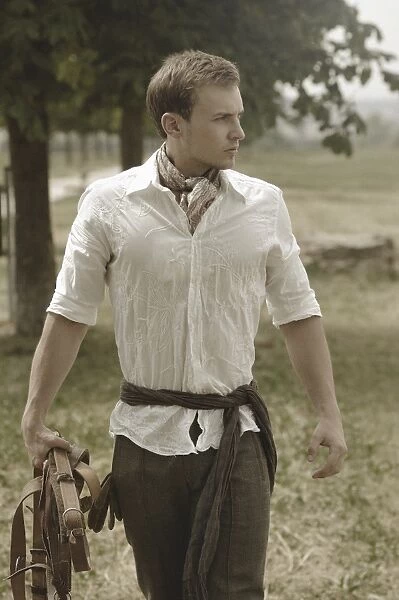 Man wearing riding clothes walking in a field in summer