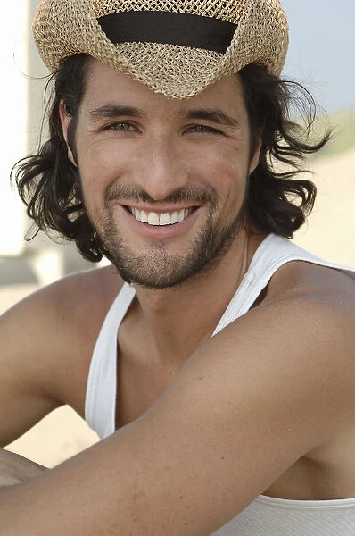 Man wearing a sun hat on a beach, smiling