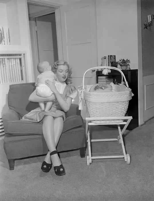 Framed Print : Marilyn Monroe Holding Baby on Couch Framed Print : Marilyn Monroe Holding Baby on Couch