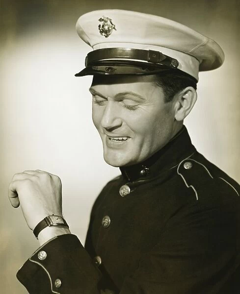 Marine in military uniform looking at wristwatch in studio, (B&W)