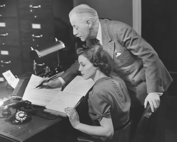 Framed Print : Mature businessman overseeing secretarys work, (B&W) Framed Print : Mature businessman overseeing secretarys work, (B&W)