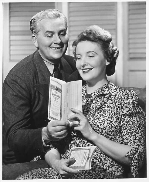 Mature couple looking at brochure, (B&W)