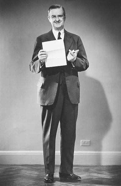 Mature man holding blank sheet of paper posing in studio (B&W), portrait