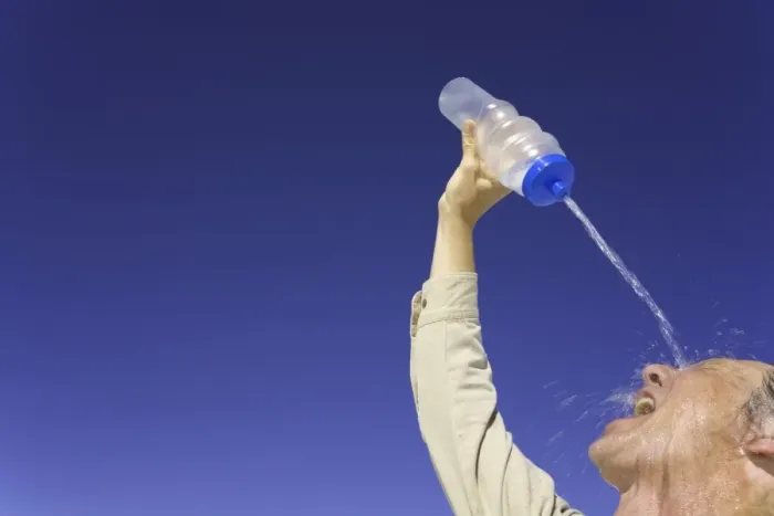 Framed Print : Mature man pouring water over face under clear sky, low angle view Framed Print : Mature man pouring water over face under clear sky, low angle view