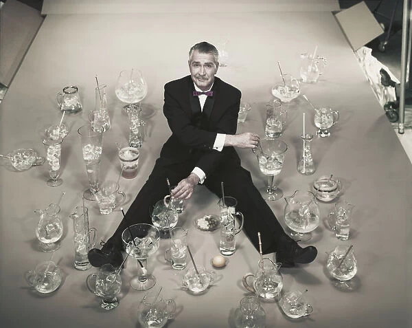 Mature man sitting with stirring glasses of ice