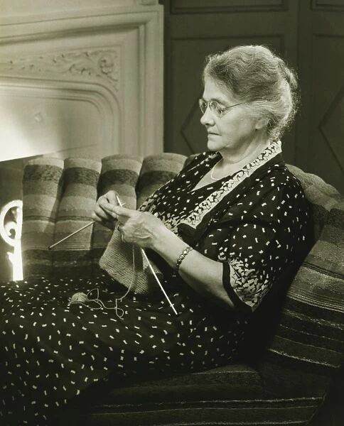 Mature woman knitting in living room, (B&W)