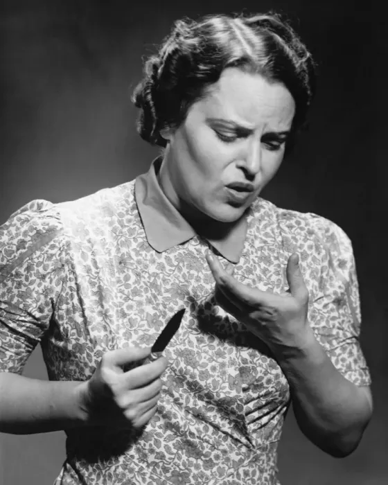 Framed Print : Mature woman looking at cut on finger in studio (B&W)