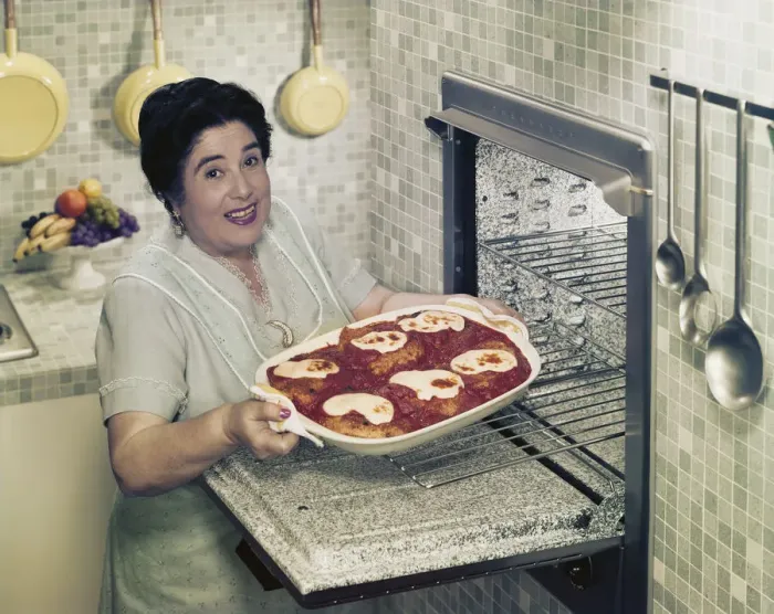 Framed Print : Mature woman putting food into oven, smiling, portrait Framed Print : Mature woman putting food into oven, smiling, portrait