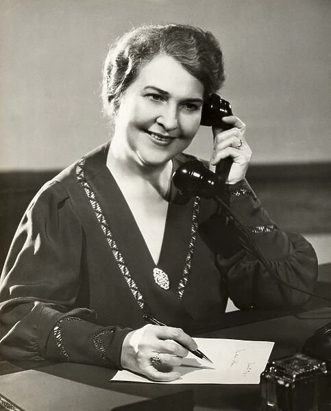 Mature woman on telephone and writing note