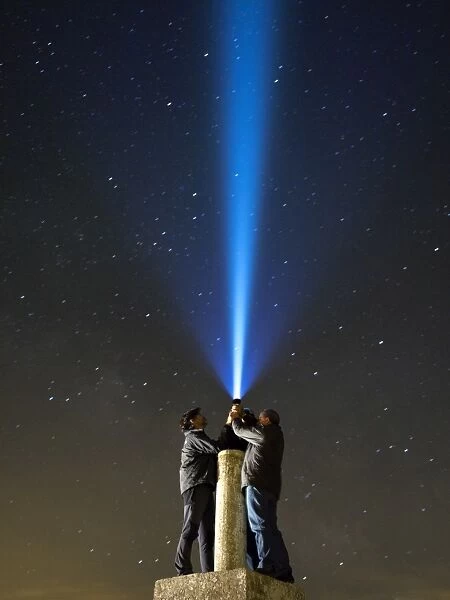 Men with his close hands illuminating the night sky with a bundle of light