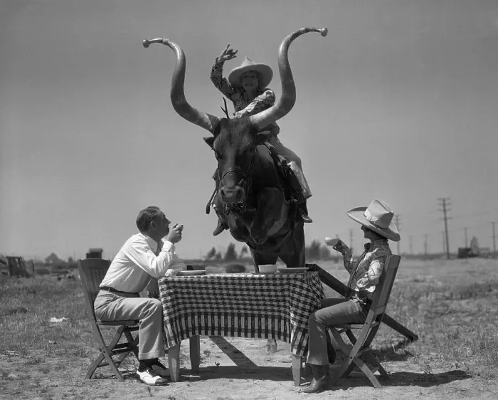 Framed Print : Men having coffee when woman jumping on bull over table Framed Print : Men having coffee when woman jumping on bull over table