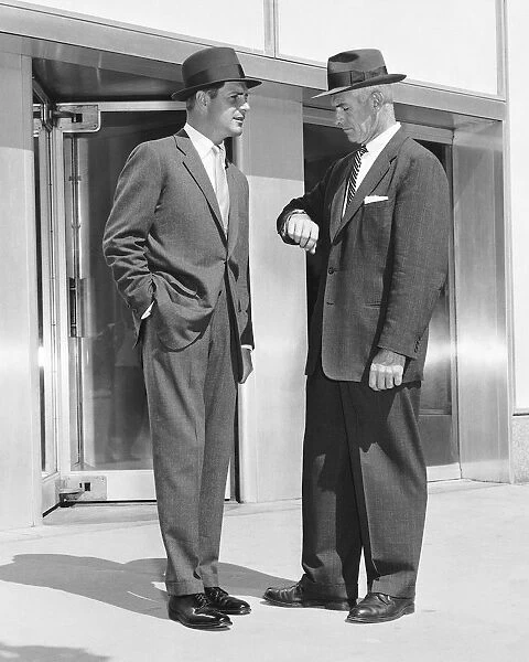 Two men standing, one checking watch