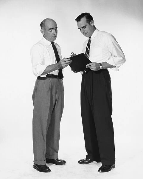 Two men standing, looking at clipboard