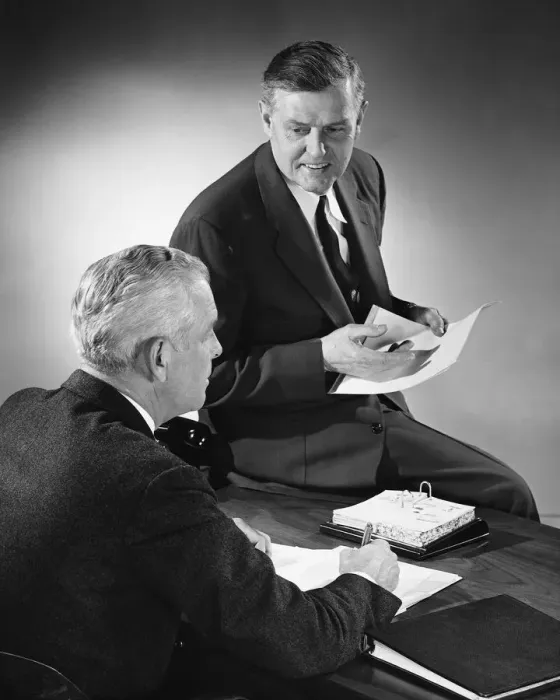 Framed Print : Two men talking, one sitting on desk Framed Print : Two men talking, one sitting on desk