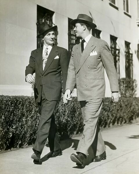 Two men walking along sidewalk
