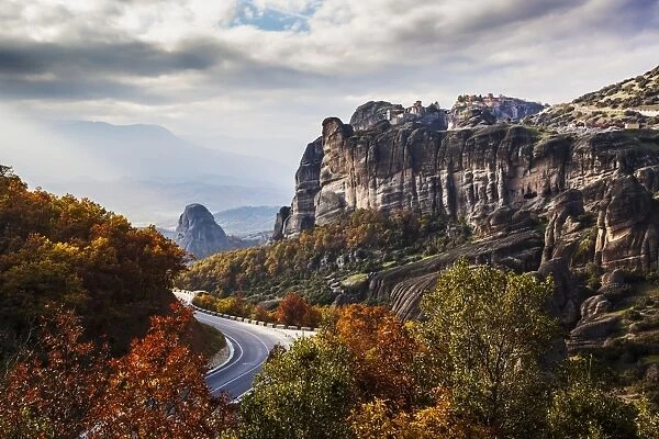 Monasteries perched on cliffs and a winding road in autumn foliage