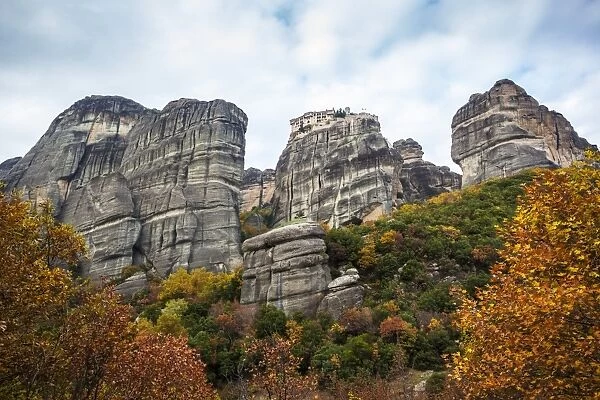 Monastery perched on a cliff with autumn foliage